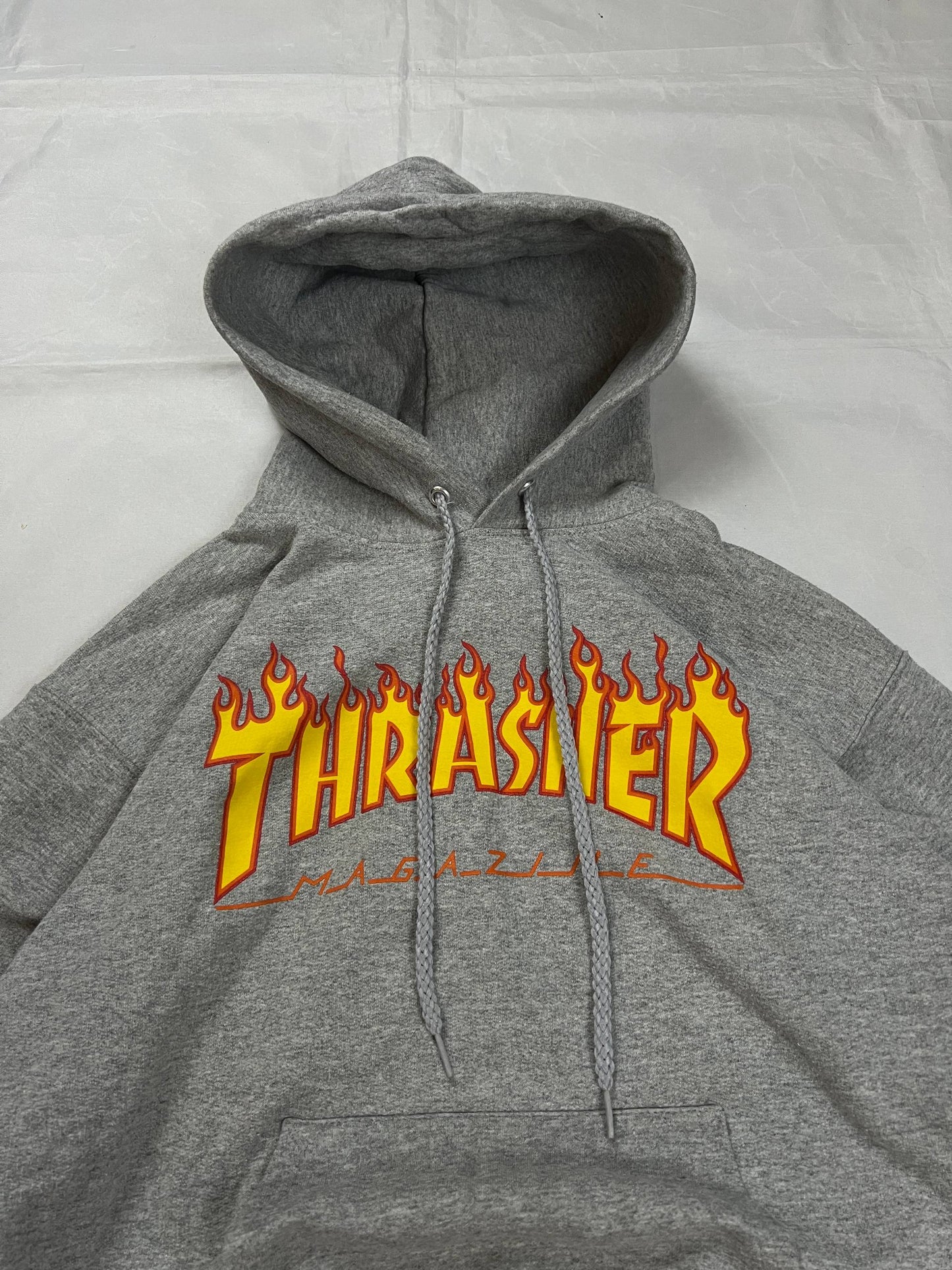 Thrasher grey hoodie with yellow and red flaming logo, kangaroo pocket, drawstring hood.