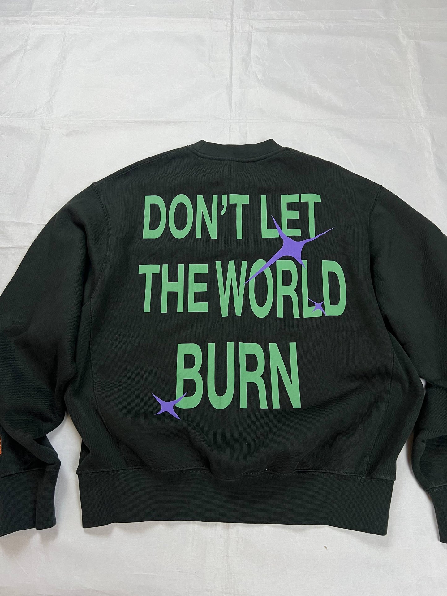 Heron Preston black graphic crewneck sweatshirt with white 'HERON' text and orange label patch.