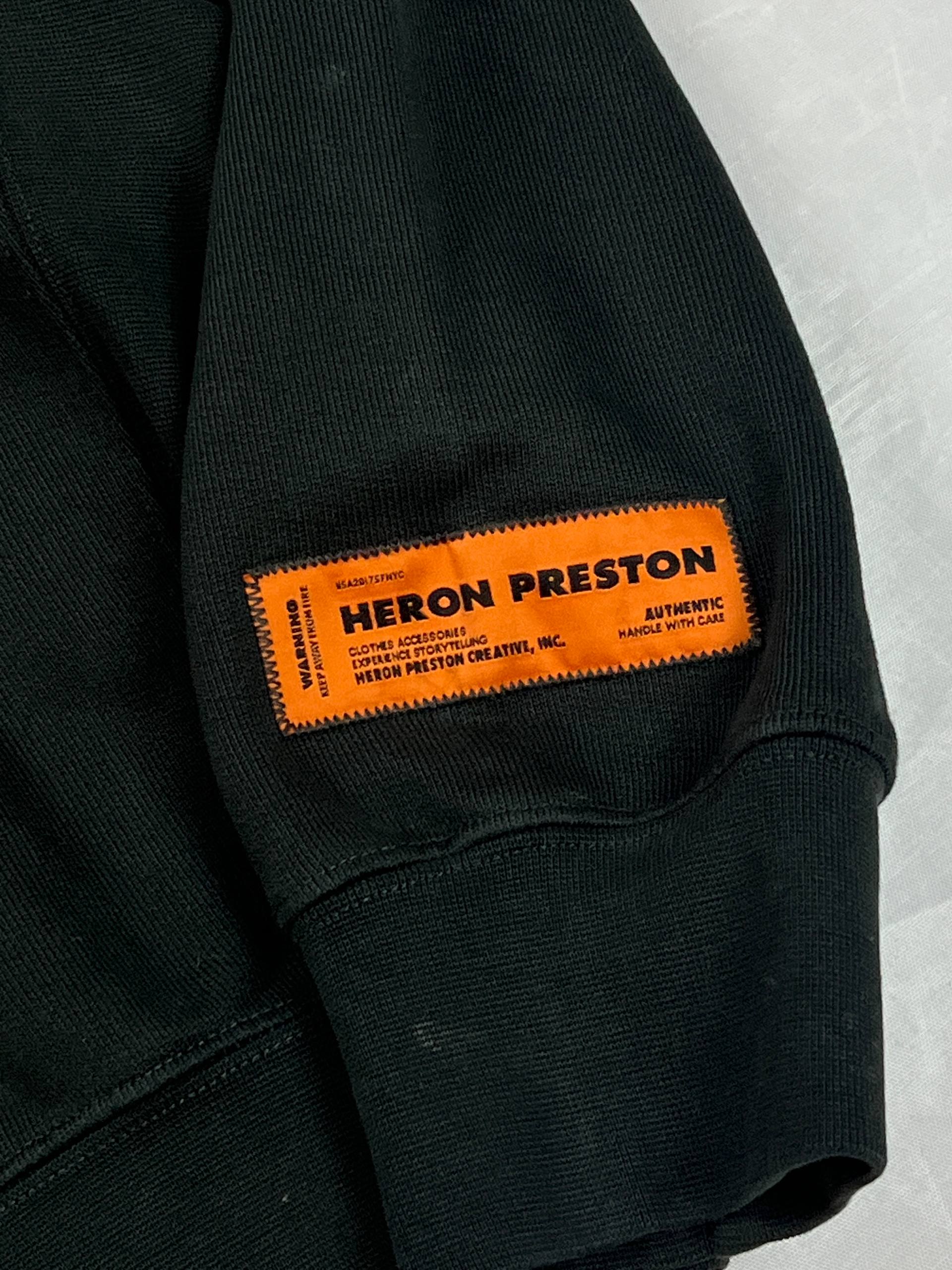 Heron Preston black graphic crewneck sweatshirt with white 'HERON' text and orange label patch.
