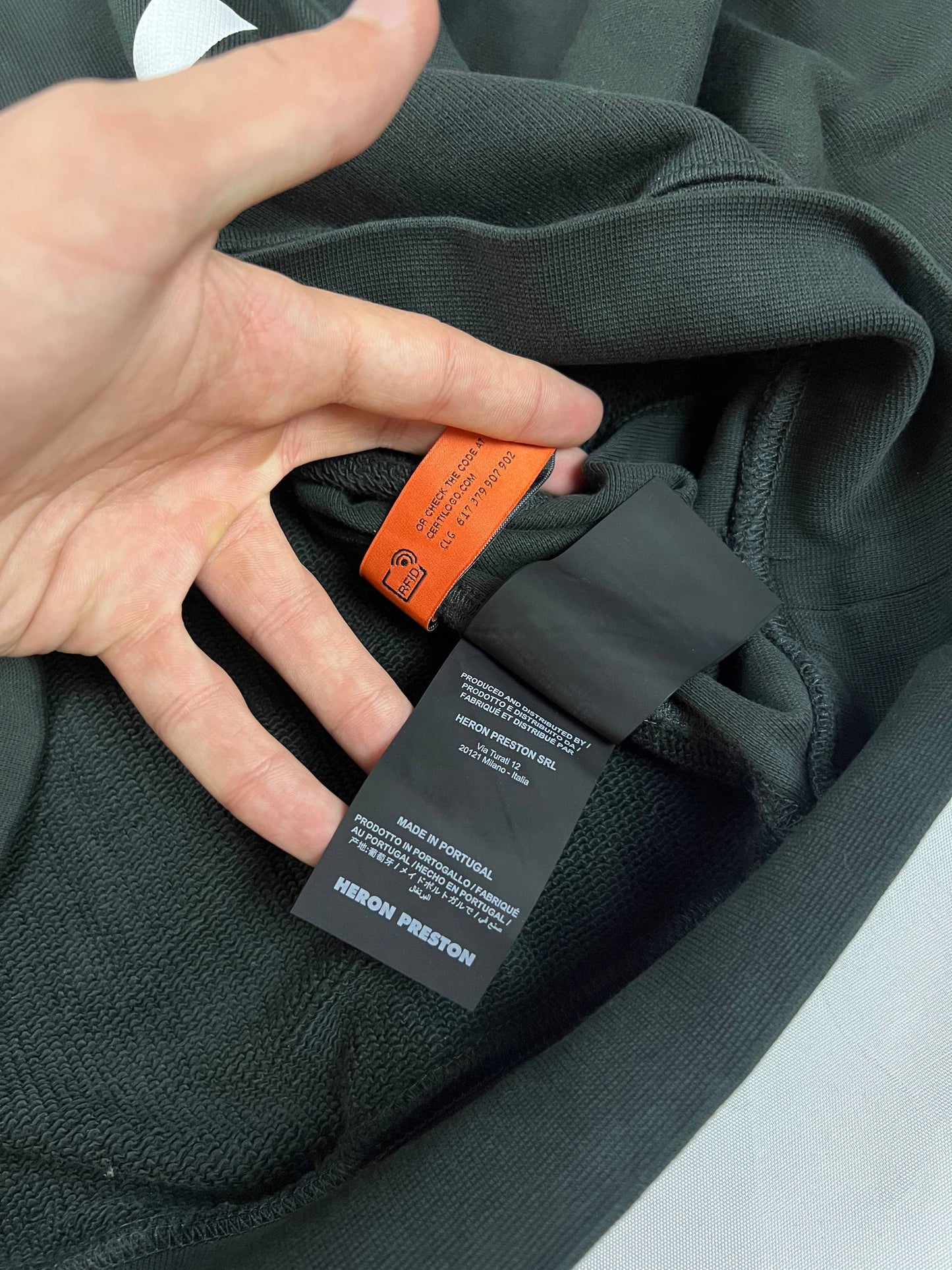 Heron Preston black graphic crewneck sweatshirt with white 'HERON' text and orange label patch.