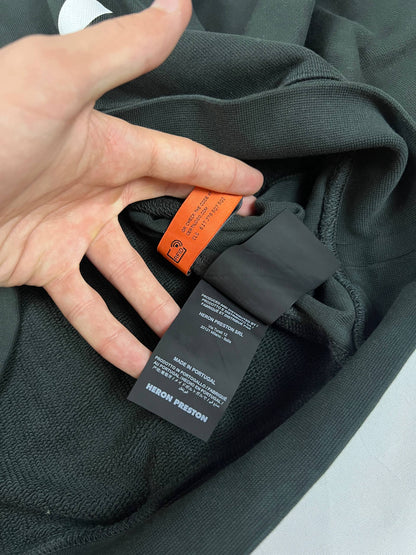 Heron Preston black graphic crewneck sweatshirt with white 'HERON' text and orange label patch.