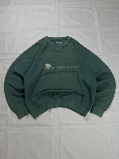Russell Athletic green crewneck sweatshirt with subtle AUTHENTIC AMERICAN SPORTS branding and ribbed cuffs.