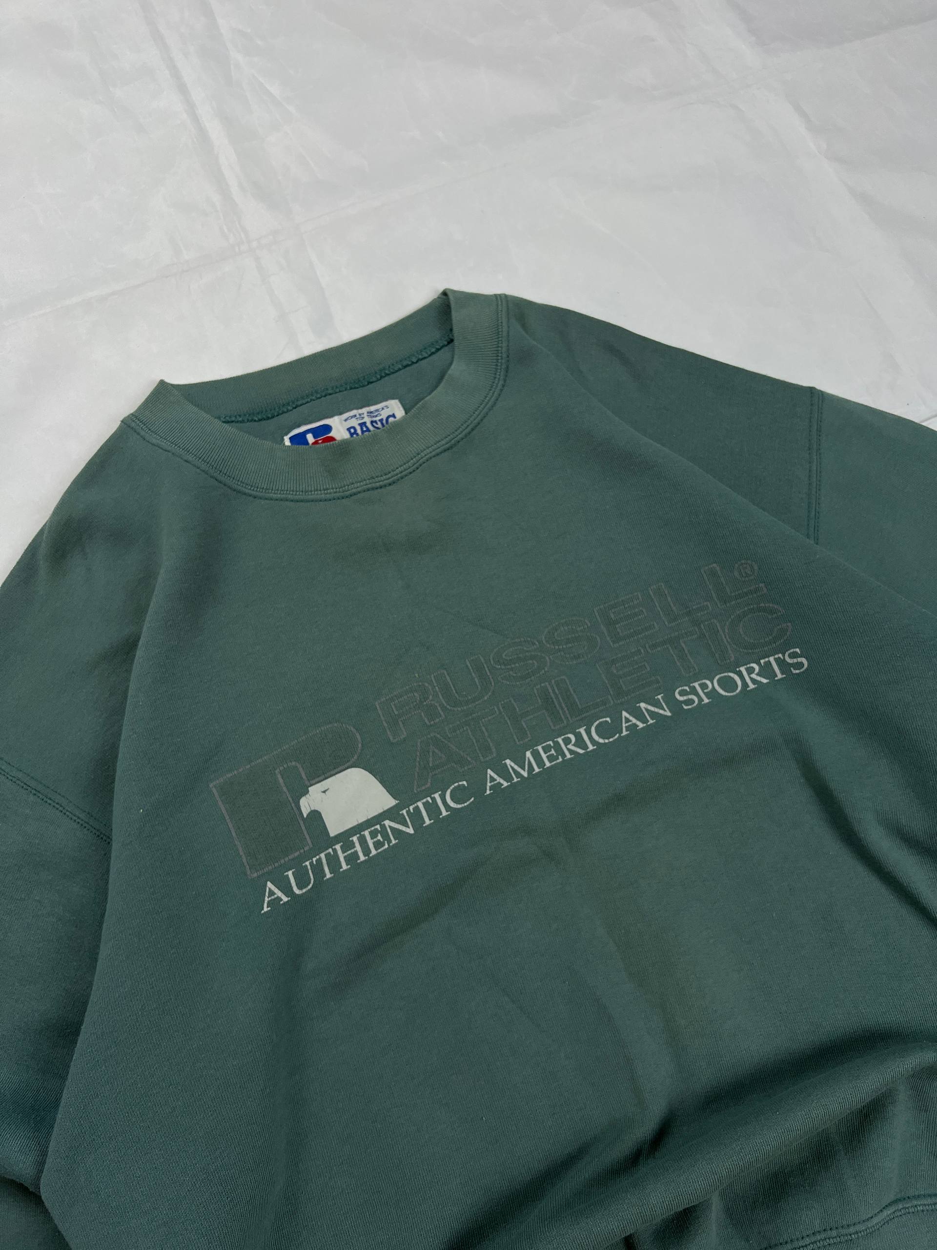 Russell Athletic green crewneck sweatshirt with subtle AUTHENTIC AMERICAN SPORTS branding and ribbed cuffs.