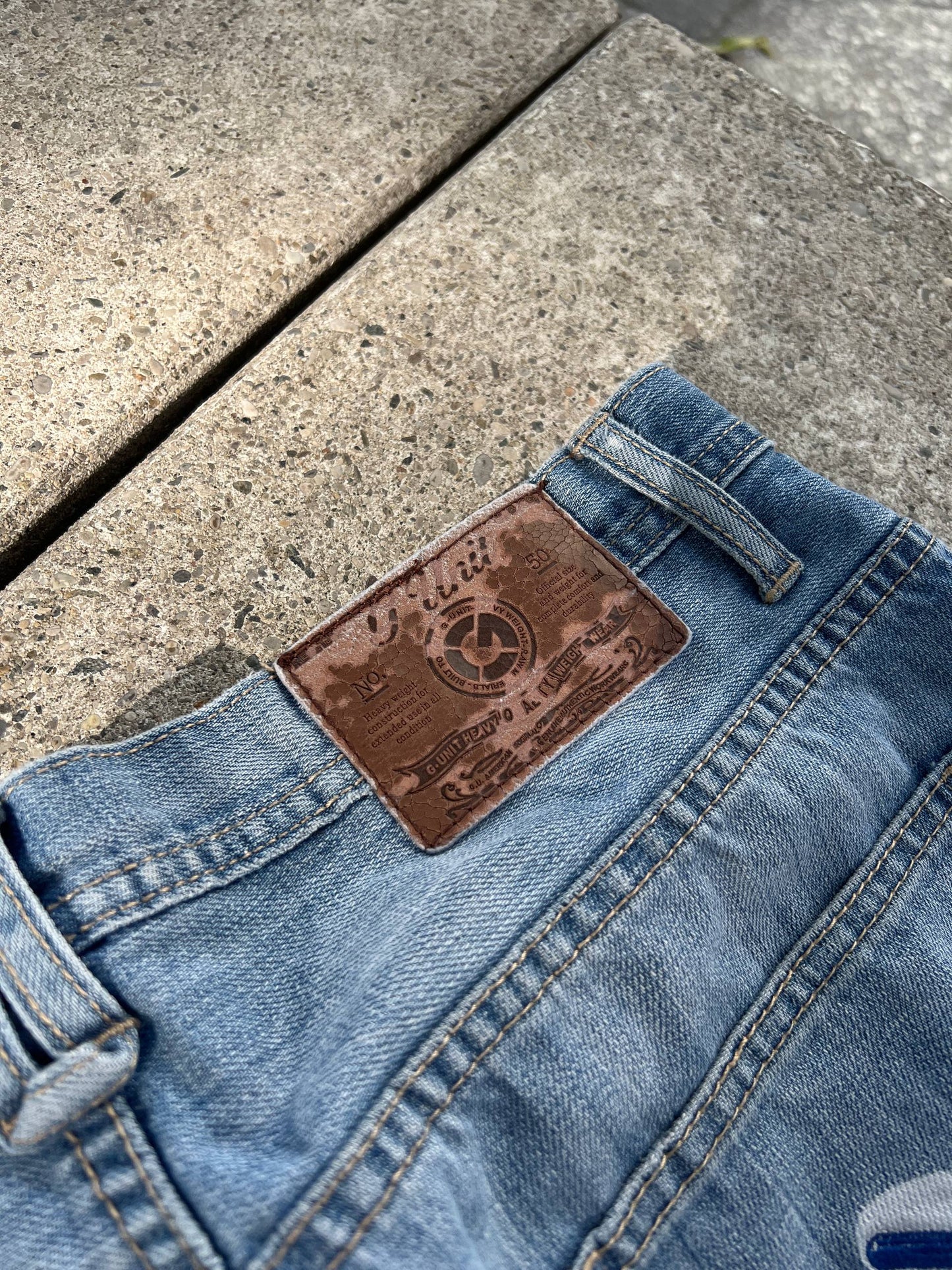 G-Unit light blue denim jeans with unique back pocket designs and leather brand patch.