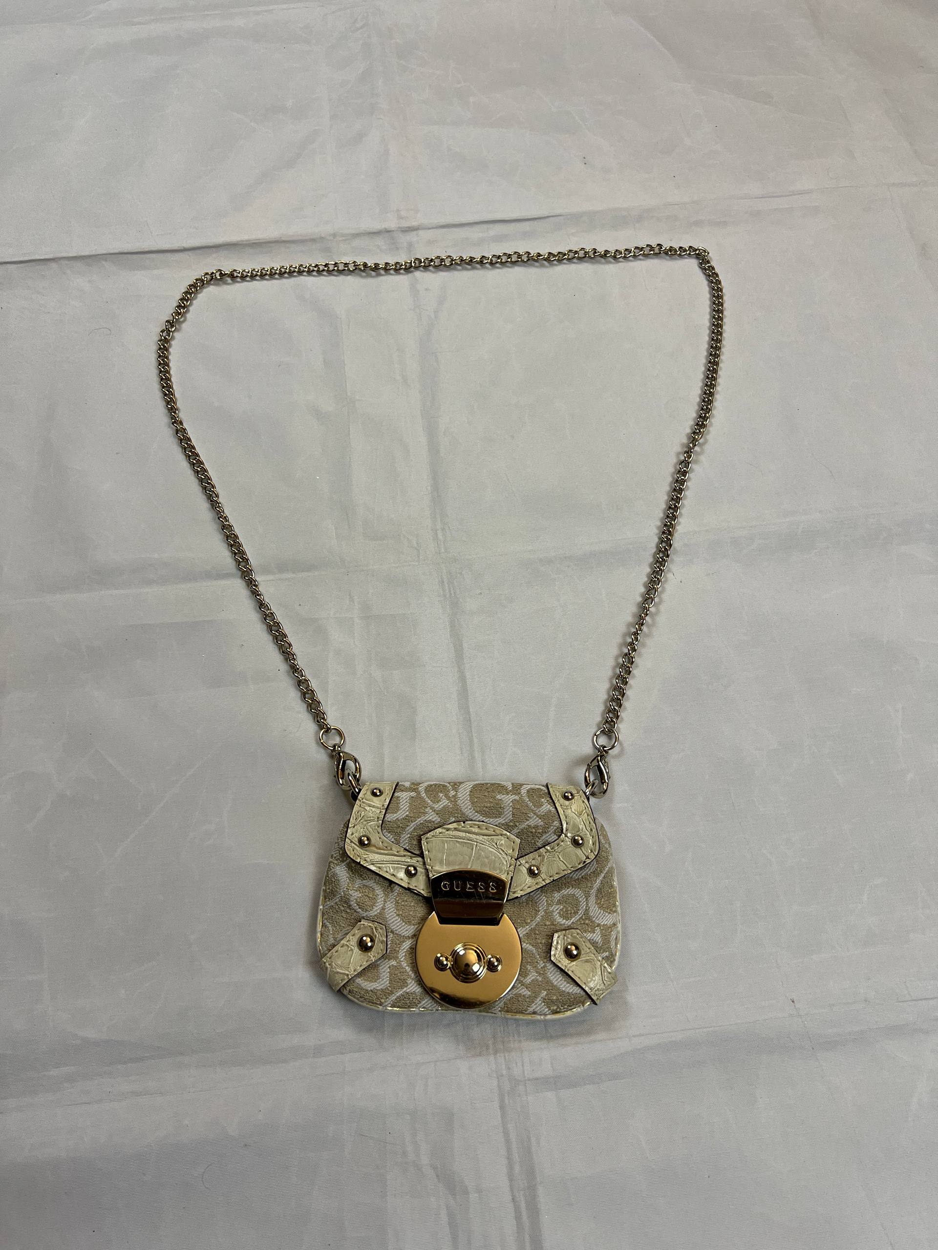 Guess beige mini crossbody bag with white signature print and gold-tone chain strap.