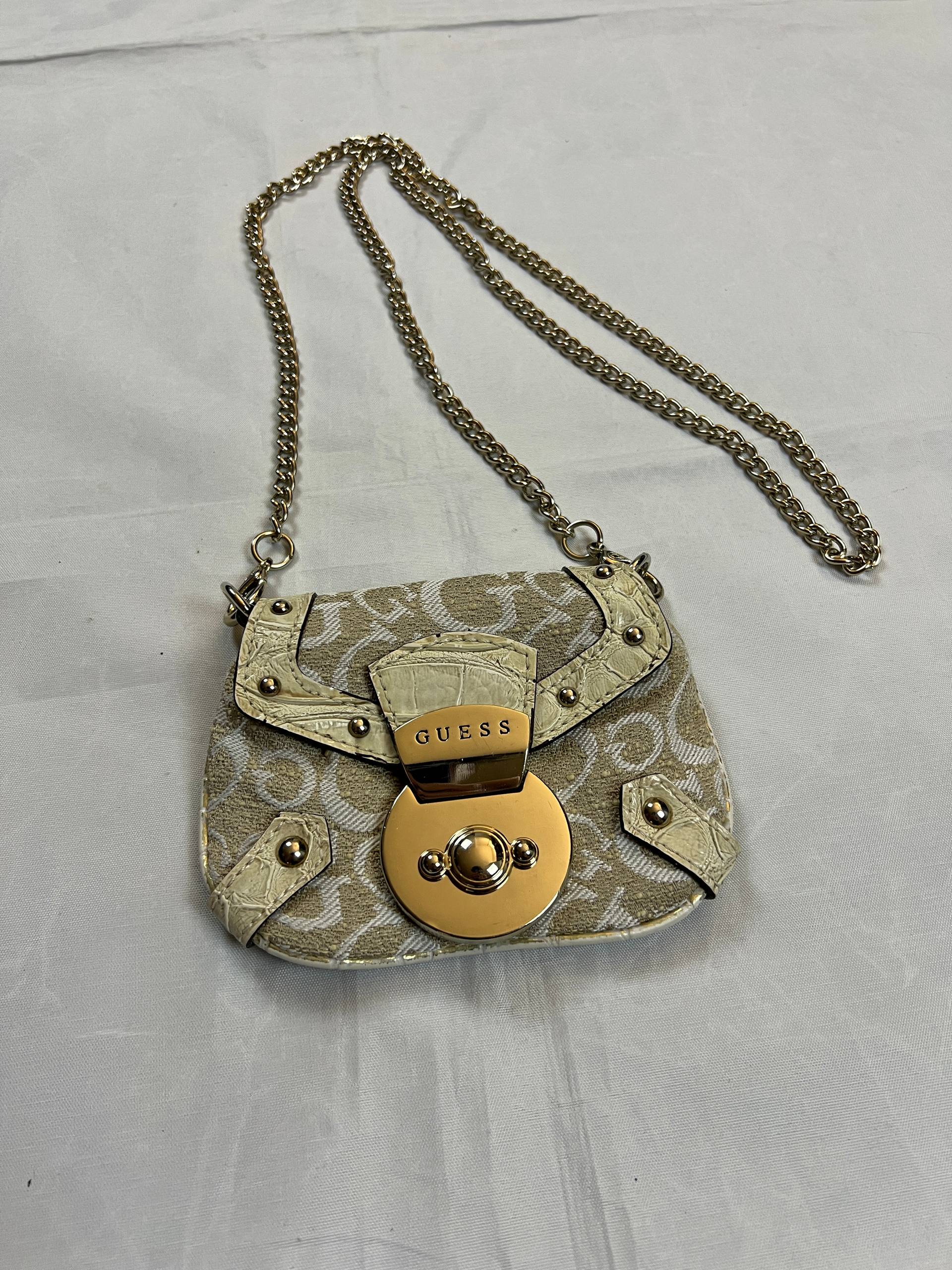 Guess beige mini crossbody bag with white signature print and gold-tone chain strap.