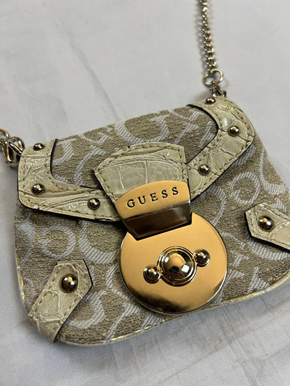 Guess beige mini crossbody bag with white signature print and gold-tone chain strap.