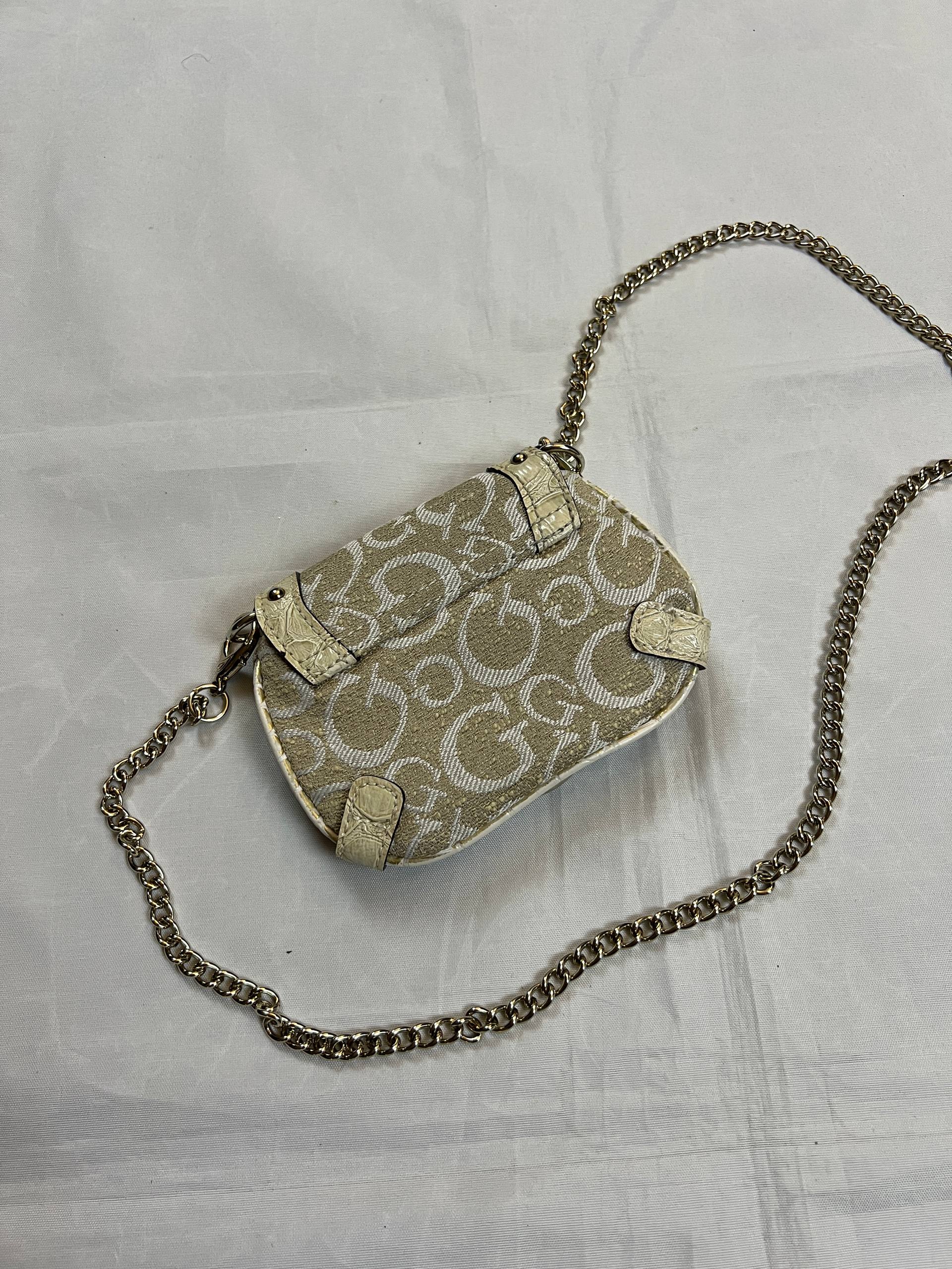 Guess beige mini crossbody bag with white signature print and gold-tone chain strap.