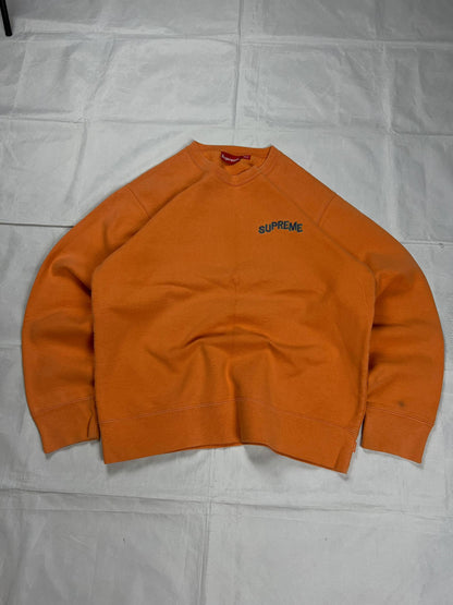 Supreme orange crewneck sweatshirt large embroidered logo on chest, soft cotton material.