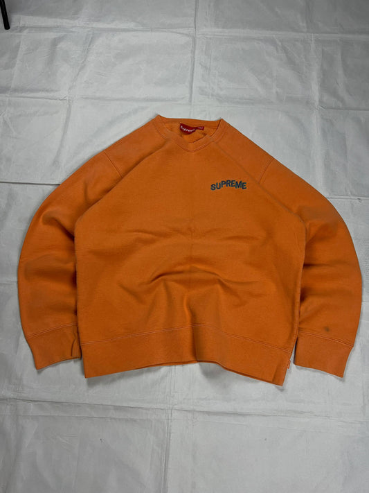Supreme orange crewneck sweatshirt large embroidered logo on chest, soft cotton material.