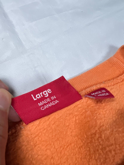 Supreme orange crewneck sweatshirt large embroidered logo on chest, soft cotton material.