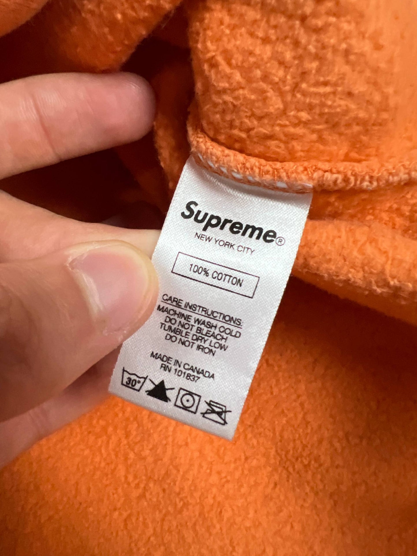 Supreme orange crewneck sweatshirt large embroidered logo on chest, soft cotton material.