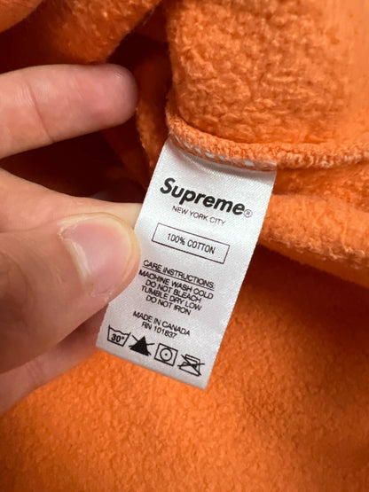 Supreme orange crewneck sweatshirt large embroidered logo on chest, soft cotton material.